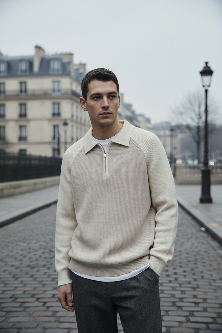 Man wearing a beige sweater with a zipper on a city street.