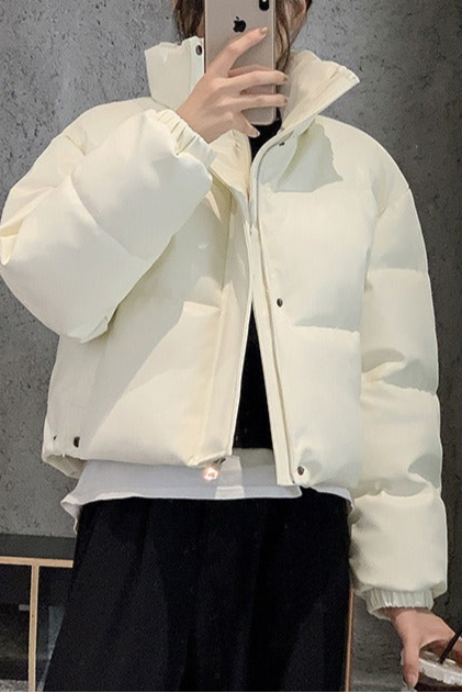 White puffer jacket worn by a person against a gray background