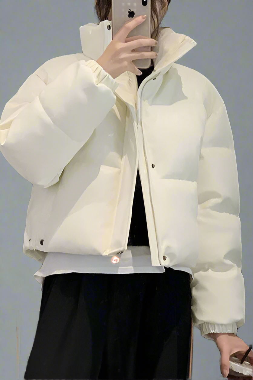 White puffer jacket worn by a person against a gray background