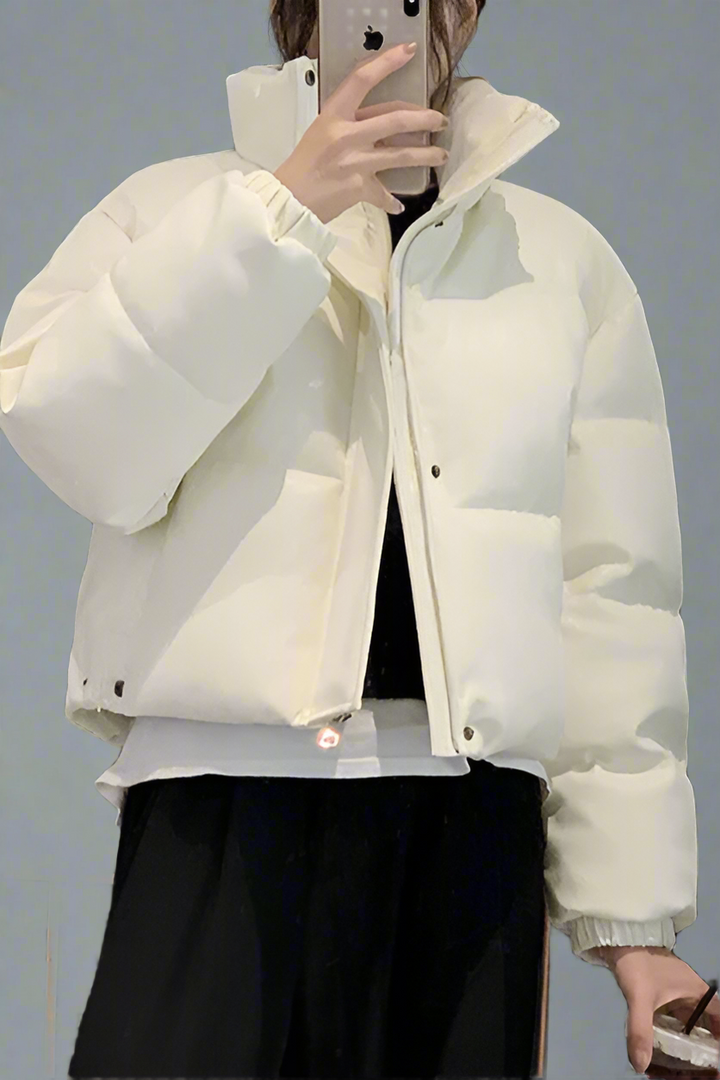 White puffer jacket worn by a person against a gray background
