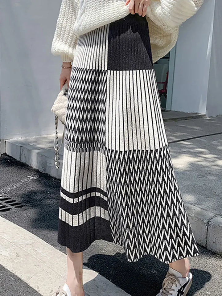 Person wearing a black and white striped skirt with a white sweater outdoors.