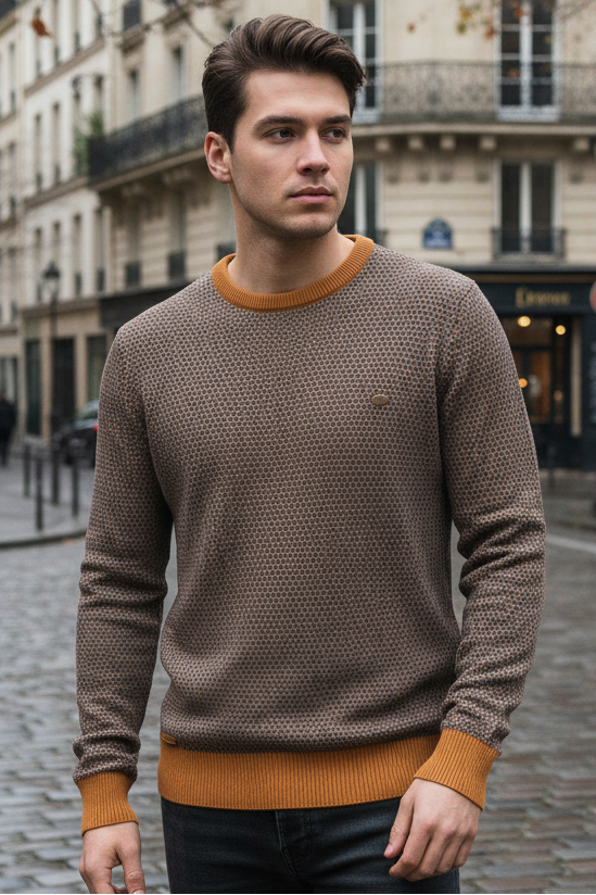 Man wearing a brown sweater on a city street with buildings in the background