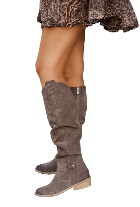 Brown knee-high boots worn with a patterned skirt on a white background