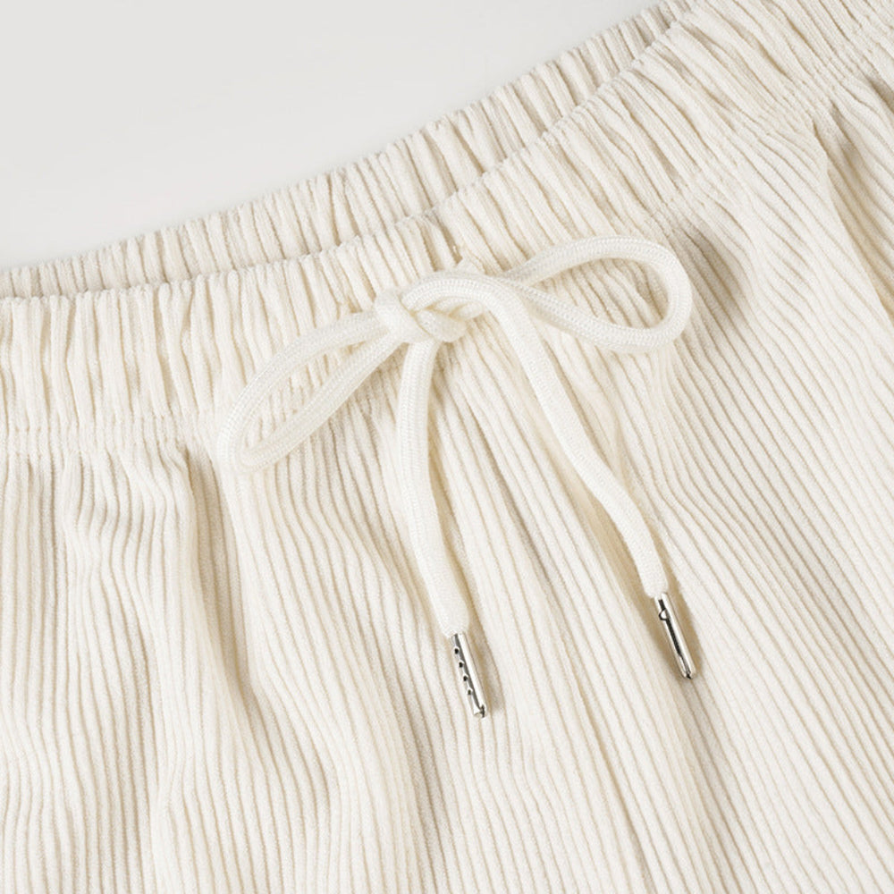 Close-up of cream-colored ribbed shorts with a drawstring on a light gray background