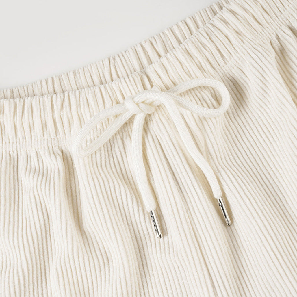 Close-up of cream-colored ribbed shorts with a drawstring on a light gray background