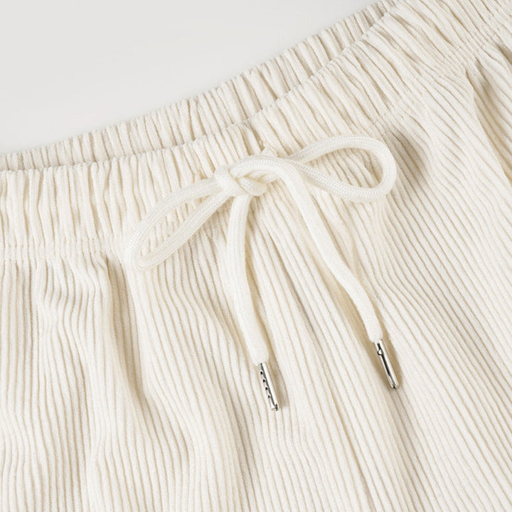 Close-up of cream-colored ribbed shorts with a drawstring on a light gray background