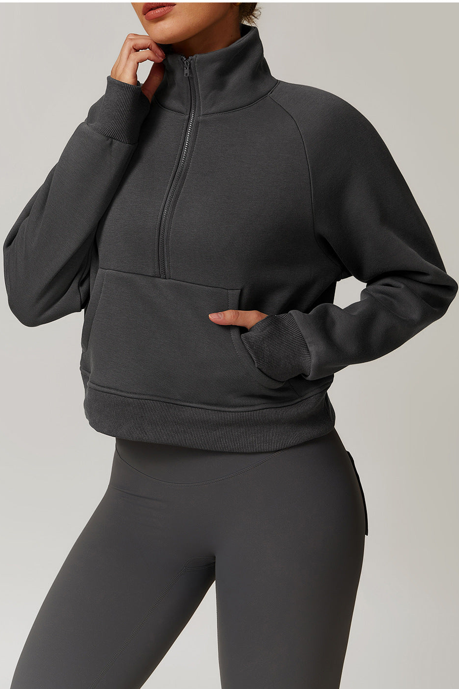 Person wearing a dark gray zip-up sweatshirt and leggings on a light gray background