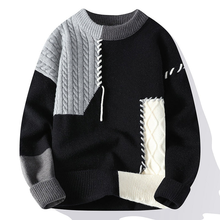 Black, gray, and white sweater with cable knit details on a white background
