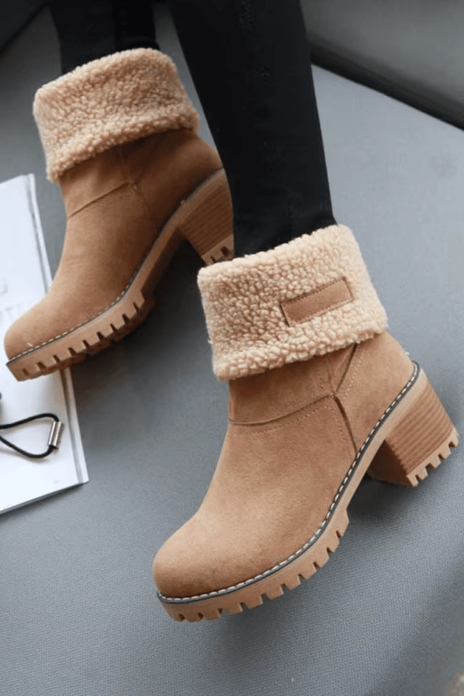 Tan winter boots with fleece lining worn by a person on a gray surface.