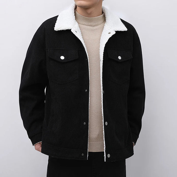 Black jacket with white fur lining worn by a person on a plain background