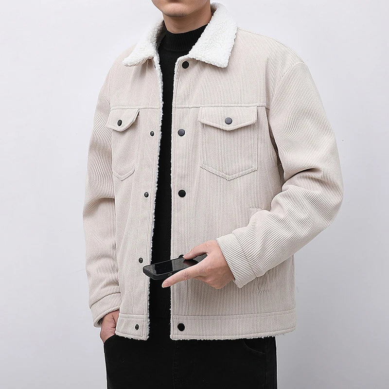 Person wearing a beige corduroy jacket with white sherpa lining on a plain background