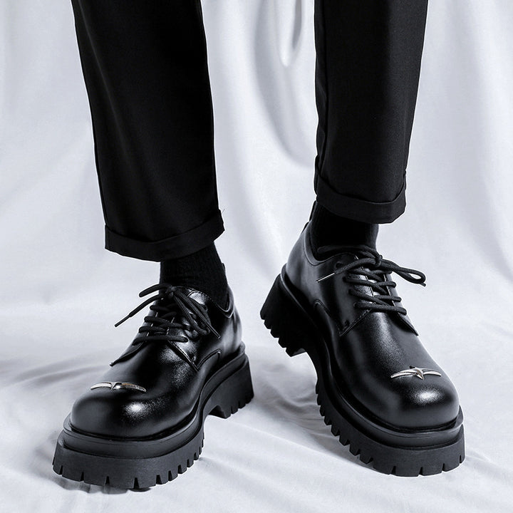 Black leather shoes worn with black pants on a white background