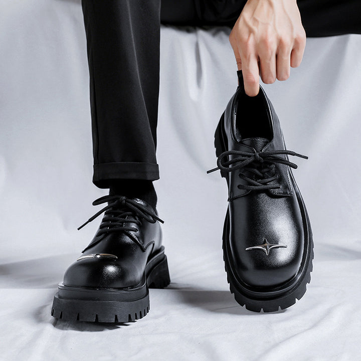 Person wearing black leather shoes with a star design on a light gray background